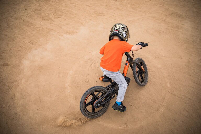 Child riding IRONe on dirt.
